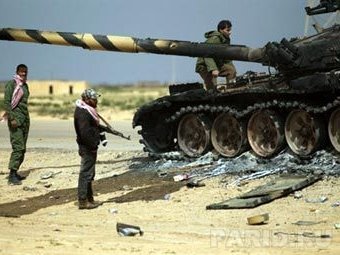 Ливийские повстанцы у сожженного танка сил Каддафи. Фото ©AFP